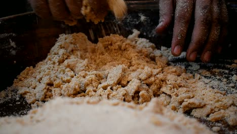 man-separating-dough-from-the-wooden-plate-from-his-hands-for-kneading