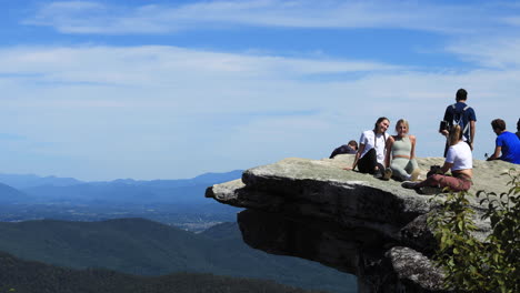 Two-girls-posing-for-a-photo-on-top-of-the-McAfee-Knob-in-Virginia-while-their-friend-takes-a-photo-of-them