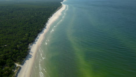 Tilt-up-from-the-turquoise-tropical-Osetnik-beach-waters-with-white-sand-to-the-sky,-Poland