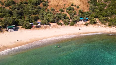 Aerial-drone-clip-over-a-beautiful-beach-in-Kavala,-Macedonia,-Greece-with-a-man-in-a-canoe-at-the-shore