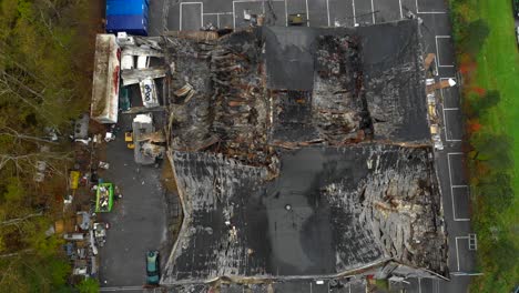 Aerial-view-of-large-building-with-destroyed-roof-damaged-by-fire,-zoom-in