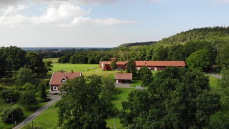 Steigende-Luftaufnahme-Von-Traditionellen-Schwedischen-Roten-Holzhäusern-Und-Wald