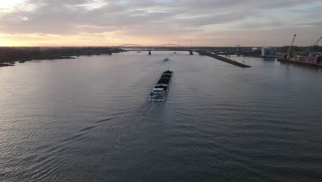 Aerial-view-of-cargo-ship-tanker-sailing-along-the-river-during-sunset