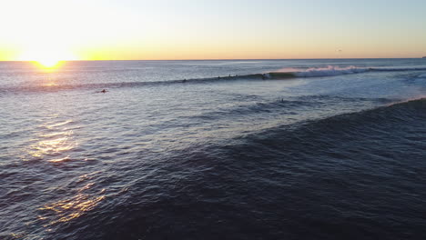 Luftaufnahme-Von-Surfern,-Die-Während-Eines-Wunderschönen-Sonnenaufgangs-Am-Sehr-Beliebten-Touristenziel-Burleigh-Heads-Gold-Coast,-Australien,-Eine-Welle-Fangen