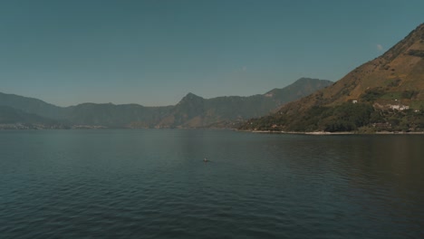 Drone-aerial-shot-of-a-man-on-a-boat-in-lake-Atitlan,-Guatemala