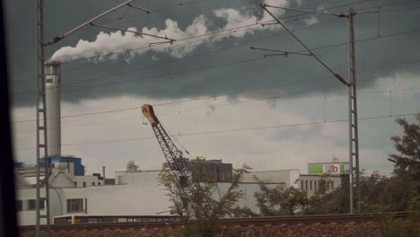 Rauch-Steigt-Aus-Dem-Schornstein-Einer-Fabrik,-Gesehen-Durch-Ein-Fenster,-Umweltverschmutzung-Und-Klimawandel