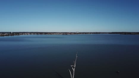 Drone-aerial-zooming-in-towards-the-land-with-dead-trees-coming-out-of-dark-blue-lake-in-Yarrawonga-on-a-sunny-day