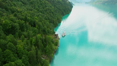 Aerial-view-of-a-boat-approaching-Geissbach-on-Lake-Brienz,-Switzerland