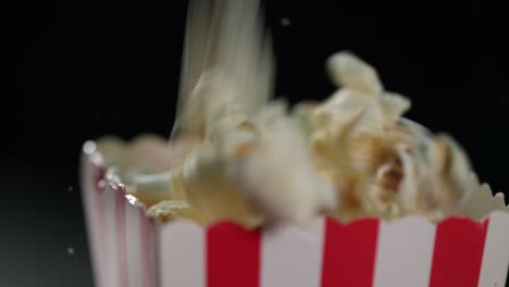 Full-frame-close-up:-Plump-fresh-popcorn-drops-into-small-striped-container