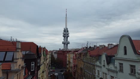 Prague-Zizkov-Tower-aerial-drone-ascending-view-from-street-between-buildings,-capital-of-Czech-Republic