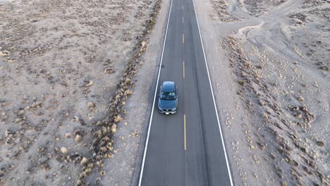 Aerial-tilt-up-shot-of-a-drone-following-a-car-and-revealing-the-road,-wilderness-around-in-Peruvian-highway