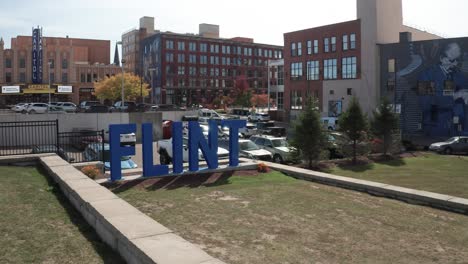 Flint,-Michigan-blue-city-sign-with-drone-video-moving-low-at-an-angle