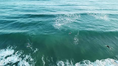 Drone-aerial-of-surfer-ducking-under-a-blue-wave-at-the-beach-on-a-summer-day
