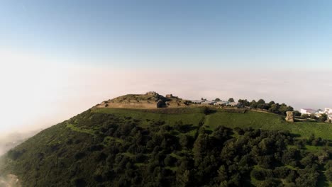 Rotierende-Drohne-Aus-Der-Luft,-Die-An-Einem-Sonnigen-Tag-Mit-Blick-Auf-Die-Landschaft-über-Die-Berge-Von-Medina-Sidonia-In-Andalusien,-Spanien,-Unter-Blauem-Himmel-Geschossen-Wurde