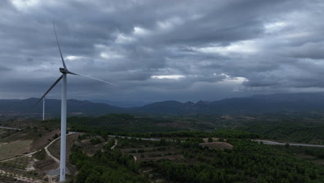 Dark-moody-sky-over-mountainous-terrain-with-a-wind-turbine-not-working