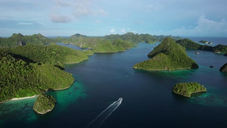 Small-boat-drives-through-in-Raja-Ampat-Indonesia,-in-between-tropical-islands,-turquoise-waters,-and-coral-reefs