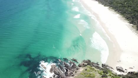 Drone-aerial-pan-up-to-show-long-stretch-of-beautiful-blue-water-and-white-sand-beach