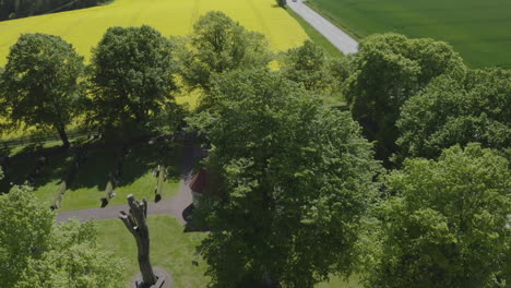 Drohnenansicht-über-Ein-Kleines-Haus,-Umgeben-Von-Bäumen-Und-Einem-Großen-Gelben-Rapsfeld
