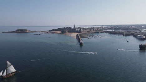 Sailing-ship-navigating-front-of-Môle-des-Noires-lighthouse-with-Saint-Malo-in-background,-Brittany-in-France