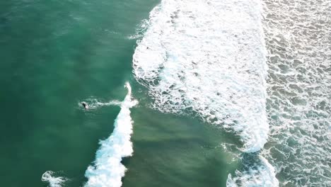 Drone-aerial-of-surfer-catching-wave-on-blue-water-on-Great-Ocean-Road-on-a-sunny-summer-day