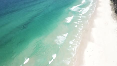 Drone-aerial-panning-down-to-beautiful-blue-beach-with-white-sand