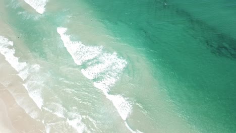 Drone-aerial-panning-up-from-beautiful-blue-beach-with-white-sand-to-forest-and-lighthouse