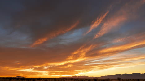 Der-Himmel-Leuchtet-Von-Gold-Bis-Leuchtend-Rot-über-Der-Mojave-wüste,-Während-Die-Sonne-Hinter-Den-Westlichen-Bergen-Untergeht---Weitwinkel-zeitraffer