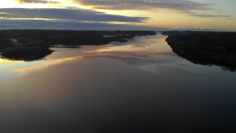 Aerial-view-of-Scandinavian-fjord-landscape,-sunset-sky-reflection,-forward