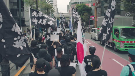 Solidarity-With-Hong-Kong-Protest-In-Tokyo,-Japan---People-Marching-In-The-Street-With-Japanese-And-Black-Flags-Waving---ascending-shot