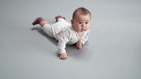 Active-Baby-In-Printed-Overall-And-Brown-Socks-Rolling-And-Lie-On-Her-Stomach