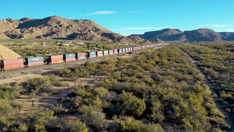 Largo-Tren-De-Carga-Que-Transporta-Carga-A-Través-Del-Desierto-De-Arizona-A-Lo-Largo-De-La-Autopista-66