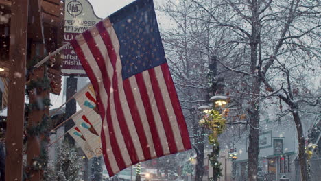 Couple-crossing-street-lined-by-USA-flags-during-Christmas-snowfall-and-new-year-festivals