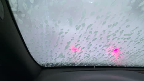 Close-up-shot-of-automatic-machine-sprays-water-to-clean-the-soap-of-the-windshield