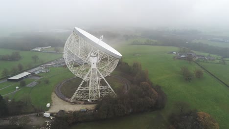 Aerial-Jodrell-bank-observatory-Lovell-telescope-misty-rural-countryside-slow-descend-side-view