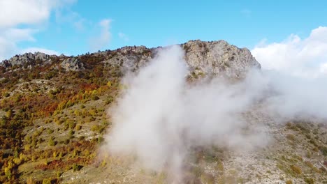 Mountain-peak-covered-in-clouds-on-a-sunny-day-drone-shot