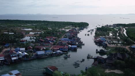 Traditional-fishing-village-in-an-estuary-on-the-south-coast-of-Cambodia-with-boats-traveling,-drone-aerial