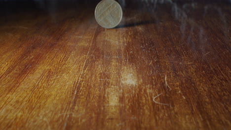 Closeup-of-10-francs-coin-flipping-on-wooden-table,-static,-slow