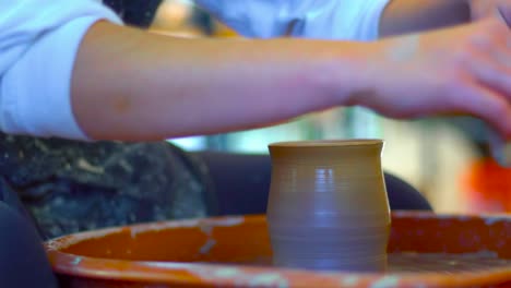 A-girl-uses-a-pottery-rib-to-shape-a-clay-pot
