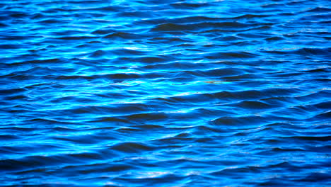 Blue-waves-on-the-surface-of-a-lake,-sea-or-ocean-in-slow-motion---background-texture