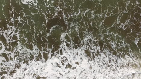 Top-Down-Aerial-View-of-Ocean-Waves-Breaking-on-Sandy-Beach-on-Sunny-Day