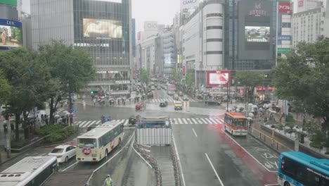 Vehicles-On-The-Go-At-Shibuya-Crossing-In-Tokyo,-Japan-On-A-Rainy-Day---wide-shot,-high-angle