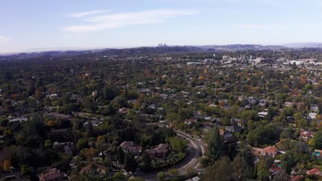 Aerial-descending-shot-of-Pasadena-neighborhood-with-Downtown-Los-Angeles-in-the-background