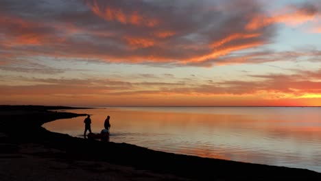 Zwei-Fischer-Waten-In-Die-Ruhige-Mündung-Der-Laguna-Madres,-Während-Sie-Während-Eines-Wunderschönen-Sonnenuntergangs-Ausrüstung-In-Einem-Kajak-Ziehen