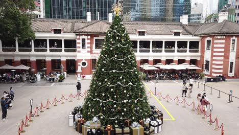 Gente-Viendo-Un-Gran-árbol-De-Navidad-En-El-Recinto-De-La-Antigua-Estación-Central-De-Policía-De-Hong-Kong-Con-Gente-Pasando