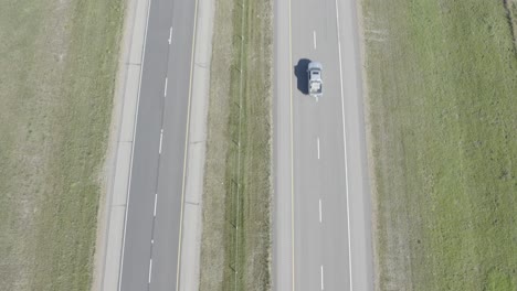 aerial-birds-eye-view-dolly-roll-over-a-the-interstate-as-theres-a-grass-field-divider-between-2-lanes-on-each-side-headed-east-west-north-or-south-on-a-sunny-summer-day-for-RVs-trucks-tankers-HWY1-2