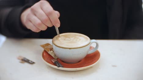 Eine-Frau-Rührt-In-Einem-Café-Ihren-Kaffee-Um