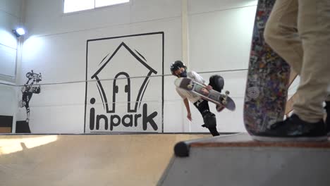 Slow-motion-shot-of-male-skateboarder-with-helmet-making-trick-on-ramp-at-indoor-skater-hall