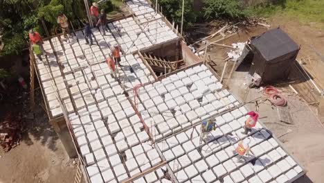 Aerial-view-of-construction-workers-working-on-the-roof-pouring-cement-to-build-roof-or-floor-structure-wearing-orange-vests