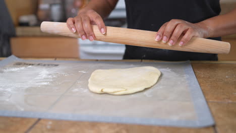 Black-woman-using-rolling-pin-on-dough-in-home-kitchen,-Slow-Motion-Close-Up