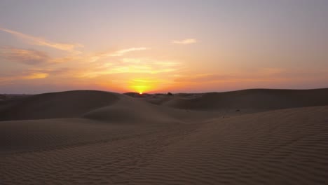Incredible-Orange-Sun-Sets-over-Horizon-of-Majestic-Silhouetted-Desert-Sand-Dunes,-establishing-shot